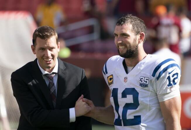 Andrew Luck shaking hands with a man in a suit.