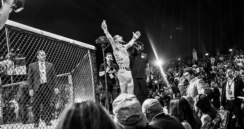 UFC fighter celebrates victory inside the Octagon in front of the crowd